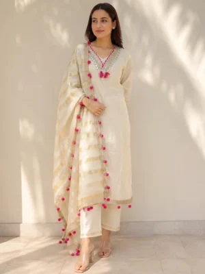 Model wearing premium off-white cotton suit with mirror work neckline, gold striped dupatta and pink pom-pom lace